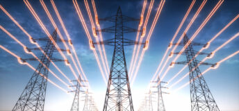 High voltage transmission towers with red glowing wires against blue sky. (Getty Images)