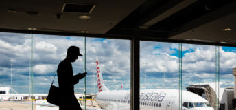 Silhouette of man standing in terminal building at Melbourne Airport, with Virgin Australia aircraft visible behind