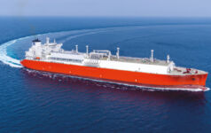 A large red and white freight ship takes a long turn in the flat, blue ocean
