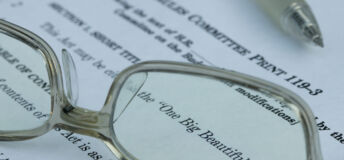 Glasses magnify text noting this is the "One Big Beautiful Bill."