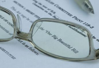 Glasses magnify text noting this is the "One Big Beautiful Bill."