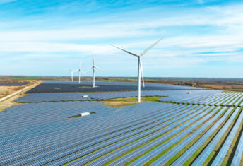 Photo of a windmill in a field with windmills in the back.