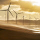 Turbines along the shoreline glowing in evening sunset light, dramatic coastal atmosphere and energy