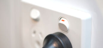 White power point outlet socket (3 pin Australian type) with switch on and black plug inserted