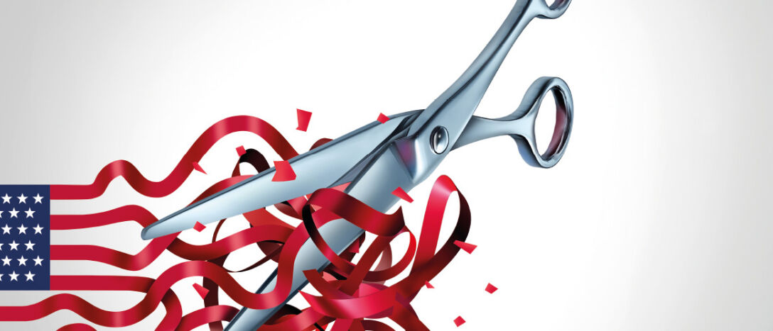 A metal pair of scissors cuts into red ribbons that form the stripes of the American flag