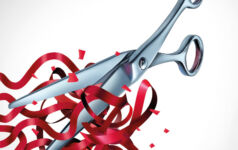 A metal pair of scissors cuts into red ribbons that form the stripes of the American flag