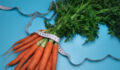 Carrots and measuring tape on the blue background. The concept of diet. Top view, flat lay. Overeating control, diet, nutritionist.