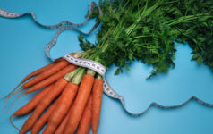 Carrots and measuring tape on the blue background. The concept of diet. Top view, flat lay. Overeating control, diet, nutritionist.