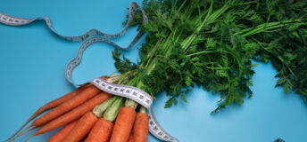 Carrots and measuring tape on the blue background. The concept of diet. Top view, flat lay. Overeating control, diet, nutritionist.