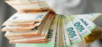 A hand holds Euro notes