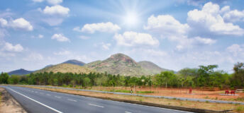 A Highway from Tirichi to Madurai, South India with trees around under a cloudy sky